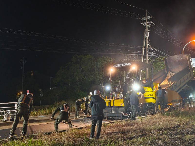 夜間工事で照明に照らされながらレーキ、コテ、ホーキそれぞれ担当の人が連係プレーで仕上げていきます。